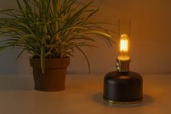 Schwarze Tischlampe mit goldenem Sockel. Der obere Teil ist aus klarem Glas.