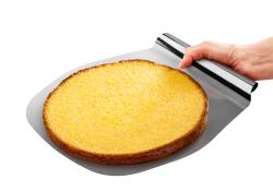 runder, goldbrauner Kuchen auf einem flachen Backblech. Eine Hand hält das Blech. Kuchenoberfläche leicht gewölbt.