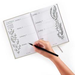 Ein offenes Notizbuch mit einem Wochenkalender für September. Eine Hand schreibt mit einem schwarzen Stift auf die Seite.