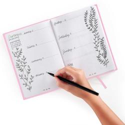 Ein Wochenplaner für September mit handschriftlichen Einträgen. Eine Hand hält einen Stift und schreibt auf die Seite.