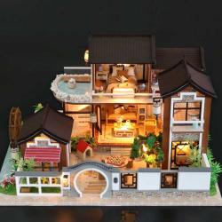 Modell eines zweigeschossigen Hauses im asiatischen Stil. Dach mit Schindeln, Balkon, Wasserstelle, Garten mit Pflanzen und einem Wasserrad.