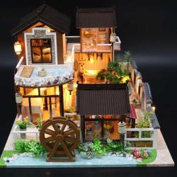 Modell eines zweigeschossigen Hauses im asiatischen Stil. Dach mit Schindeln, Balkon, Wasserstelle, Garten mit Pflanzen und einem Wasserrad.