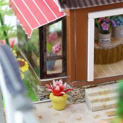 Modell eines zweigeschossigen Hauses im asiatischen Stil. Dach mit Schindeln, Balkon, Wasserstelle, Garten mit Pflanzen und einem Wasserrad.