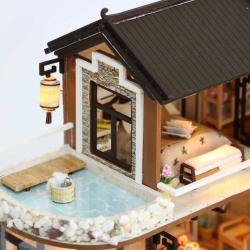 Modell eines zweigeschossigen Hauses im asiatischen Stil. Dach mit Schindeln, Balkon, Wasserstelle, Garten mit Pflanzen und einem Wasserrad.