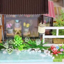Modell eines zweigeschossigen Hauses im asiatischen Stil. Dach mit Schindeln, Balkon, Wasserstelle, Garten mit Pflanzen und einem Wasserrad.