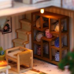 Modell eines zweigeschossigen Hauses im asiatischen Stil. Dach mit Schindeln, Balkon, Wasserstelle, Garten mit Pflanzen und einem Wasserrad.