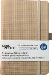 Beige Notizbuch im A6 Format mit karierten Seiten. Es hat ein Gummiband und eine Stiftschlaufe.