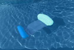 Schwimmliege mit zwei aufblasbaren Kopfstützen. Eine Kopfstütze ist blau, die andere hat ein geometrisches Muster in mintgrün und weiß. Die Liegefläche ist aus Netzmaterial.
