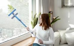 Fenstersauger mit blauer Halterung und transparentem Behälter. Hat einen Sprühmechanismus.