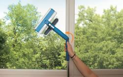 Fenstersauger mit blauer Halterung und transparentem Behälter. Hat einen Sprühmechanismus.