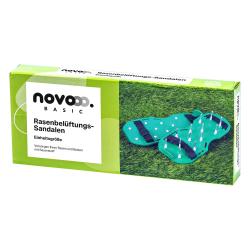 Grüne Rasenbelüftungssandalen mit langen Stiften. Verpackung zeigt die Sandalen auf Gras.