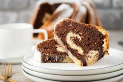 Buchcover mit dem Titel 'Mann backt Kuchen'. Abgebildet ist ein Gugelhupf mit einer hellen Füllung und Puderzucker.