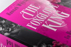 Buchcover mit dem Titel 'The Foxglove King'. Dominierende Farben sind Pink und Schwarz, mit einer goldenen Krone.