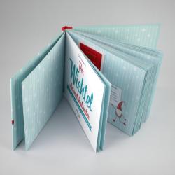 Aufklappbares Fotobuch mit hellblauem, winterlichem Design. Vorderseite zeigt den Titel Der Wichtel Adventskalender in roten und blauen Buchstaben.