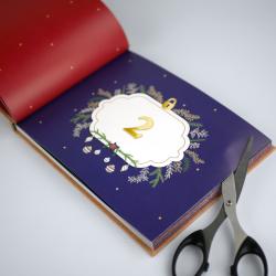 Offenes Buch mit dunklem Hintergrund und einer weißen Seite. Die Seite zeigt eine große goldene Zahl zwei in einer dekorativen Umrahmung.