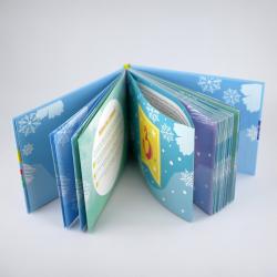 Offenes Buch mit blauer Winterdekoration. Seiten mit Schneeflocken und winterlichen Motiven, buntes Cover im Hintergrund.