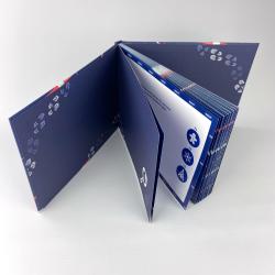 Aufklappbares Produkt mit blauer Farbgestaltung und weißen Mustern. Innen sind Symbole und Text sichtbar.