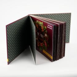 Offenes Fotobuch mit mehreren Seiten. Die sichtbare Seite zeigt eine festliche Weihnachtsdekoration mit Tannenzweigen, Kerzen und Weihnachtskugeln.