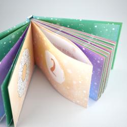 Offenes, bunt gestaltetes Buch mit mehreren Seiten in verschiedenen Farben und Mustern. Die Seiten sind mit winterlichen Motiven und Zahlen versehen.