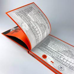 Offenes Buch mit orangefarbenem Einband. Die Seite zeigt Text in deutscher Sprache und eine kleine Illustration eines Geschenks.