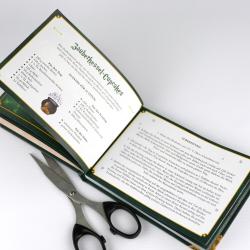 Offenes Buch mit grüner Umrandung, enthält Rezeptanleitung für Backer Keks. Seite mit Zutaten und Zubereitungsschritten, kleine Illustration eines Topfes.
