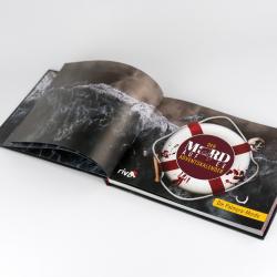 Offenes Buch mit dunklen Meereswellen auf den Seiten. Auf der rechten Seite liegt ein Rettungsring mit Blutspuren und einem Schädel, mit dem Titel Der MORD EX ADVENTSKALENDER und der Unterzeile Die Palmyra-Morde.