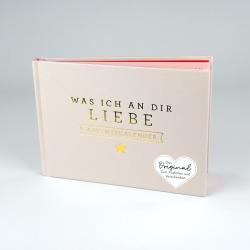 Helles, pastellfarbenes Buch mit goldener Aufschrift auf dem Cover. Der Titel lautet Was ich an dir Liebe Adventskalender, mit einem kleinen goldenen Stern und einem Herz mit Text.