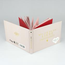 Offenes Buch mit weißem und roten Einband. Auf dem Einband steht in goldener Schrift 'Was ich an dir liebe' und 'Adventskalender'.