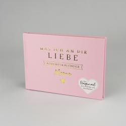 Pinke Buchhülle mit goldener Schrift. Der Titel lautet Was ich an dir Liebe Adventskalender Mama, mit einem kleinen goldenen Stern und einem weißen Herz mit Text.
