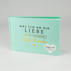 Helles Buch mit Titel Was Ich An Dir Liebe. Cover in Mintgrün mit goldener und schwarzer Schrift. Herzförmiger Aufkleber mit Text zum Ausfüllen.