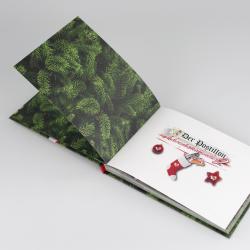 Offenes Buch mit Weihnachtsmotiven. Auf der rechten Seite ist eine Weihnachtskarte mit Tannenzweigen, Weihnachtsbaumkugel, Socke und Stern.