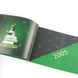 Offenes Buch mit einer Illustration eines Bücherstapels und Schneeflocken im Hintergrund. Die Seite zeigt das Jahr 2005 und eine grüne Fläche.