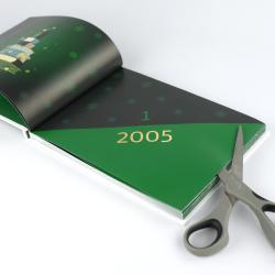Offenes Buch mit grüner und schwarzer Gestaltung. Seite zeigt Jahreszahl 2005 und eine große Zahl 1, Schneeflocken als Dekoration. Schere liegt an der unteren rechten Ecke.