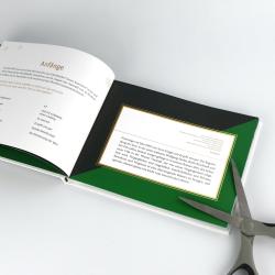 Offenes Buch mit schwarzem und grünem Einband. Die Seite zeigt einen Textblock mit Überschrift und kurzen Textpassagen.