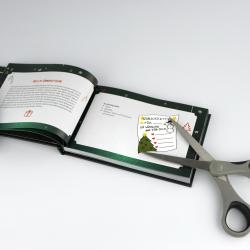 Offenes Buch mit Weihnachtsmotiven, darunter ein Weihnachtsbaum, Schneemann und Geschenk. Eine Schere liegt auf der rechten Seite, schneidet eine Seite aus.