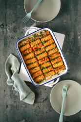 Auflauf mit goldbraun frittiertem Tofu, garniert mit grünen Frühlingszwiebeln. Das Gericht ist in einer rechteckigen weißen Form serviert.