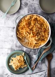 Auf dem Bild ist eine große Auflaufform mit Pasta und Käse. Die Oberfläche ist goldbraun und knusprig.