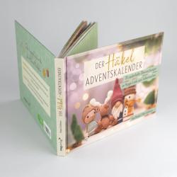 Offenes Fotobuch mit bunten Seiten, auf einer Seite eine große weiße Zahl sieben in einem Kranz aus Blättern. Die Seiten sind mit verschiedenen Mustern und Texten gestaltet.