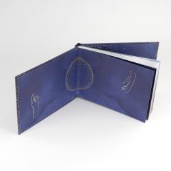 Ein aufgeschlagenes Buch mit einem blauen Cover. Illustrationen von Händen und Punkten sind sichtbar.