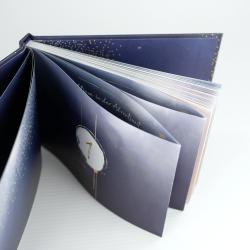 Ein Buch mit einem dunkelblauen Einband und goldenen Akzenten. Die Seiten sind farbig und zeigen die Zahl 1.