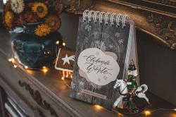 Adventskalender mit Holzoptik und der Aufschrift Oeffnende Worte. Daneben eine weiße Figur eines Ritters auf einem weißen Pferd, umgeben von Lichterketten und einer Vase mit gelben und braunen Blumen.