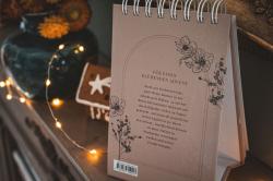 Kalender mit Spiralbindung, beige Hintergrund, schwarze Linien und Blumenmuster. Text über Advent und Papierkunst, keine Bilder.