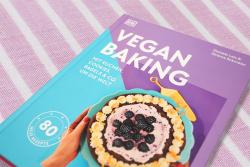 Buchcover mit dem Titel 'Vegan Baking'. Farbige Gestaltung in Lila und Rosa, zeigt einen Kuchen mit Beeren.