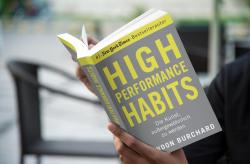 Buchcover mit dem Titel 'HIGH PERFORMANCE HABITS'. Grauer Hintergrund mit gelben Schriftzügen und dem Autorennamen Brendon Burchard.