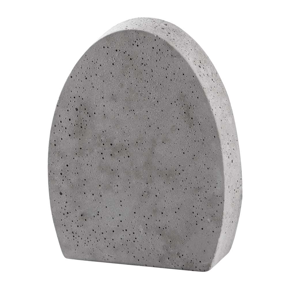 Grauer Betonblock in ovaler Form. Oberfläche mit kleinen Löchern.