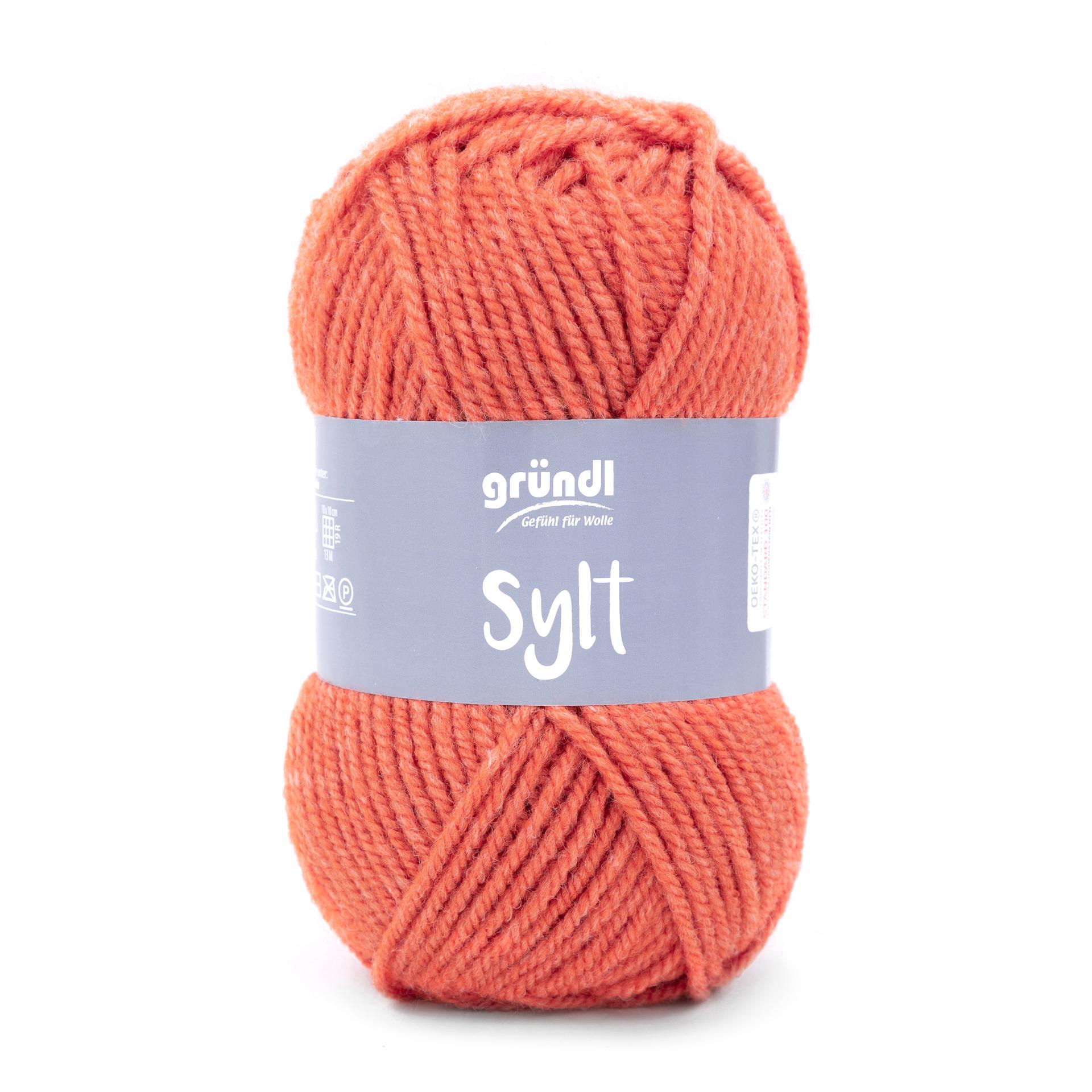 Knäuel aus orangefarbenem Garn. Beschriftung mit dem Namen 'Sylt' und Hersteller 'gründl'.