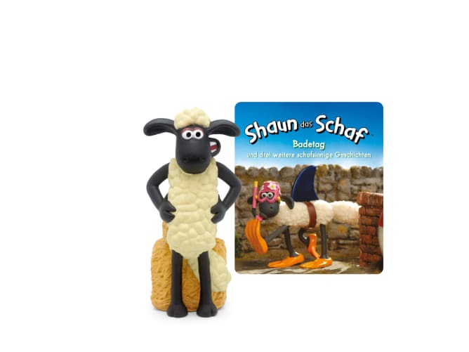 Figur eines Schafes mit schwarzem Gesicht und Beinen. Steht auf einem Heuballen. Neben der Figur ein Buchcover mit dem Titel 'Shaun das Schaf: Badetag' und weiteren Geschichten.