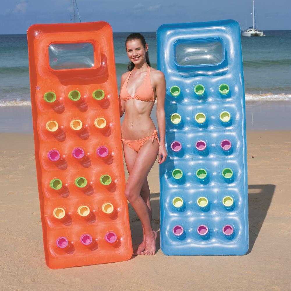Frau in orangefarbenem Bikini steht zwischen zwei aufblasbaren Liegen. Eine Liege ist orange, die andere blau.