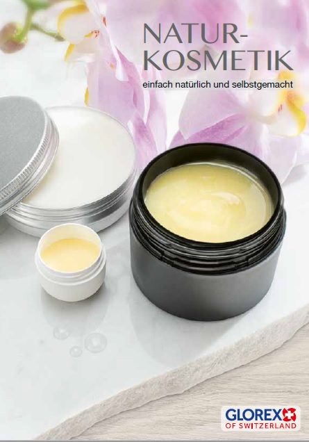 Zwei Cremetöpfe, einer schwarz und einer klein und weiß. Hintergrund mit blühenden Orchideen.