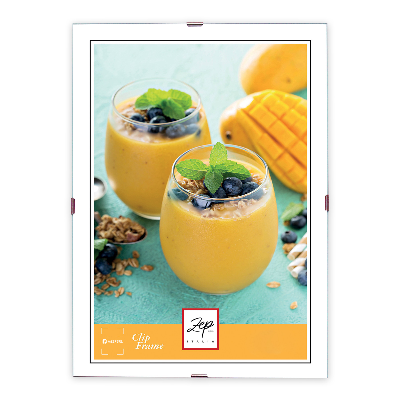 Zwei Gläser mit gelbem Smoothie, garniert mit Blaubeeren und Minze. Im Hintergrund frische Mango und Haferflocken.